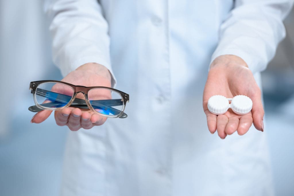 eyeglasses and contact lenses in hand