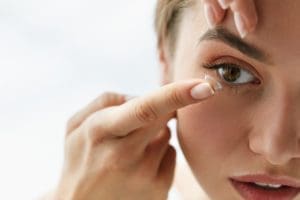 woman putting contact lens in her eyes