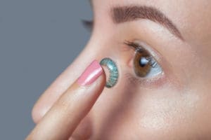 woman holding a blue contact lens
