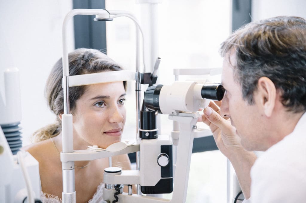 Eye doctor examining the eyes of his girl patient
