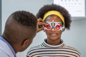 A young woman is being examined by an optometrist for the difference between nearsightedness and farsightedness.