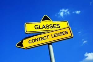 A yellow sign pointing to the options: contact lenses vs glasses.