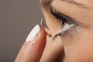 A woman is putting multifocal contact lenses on her eye.