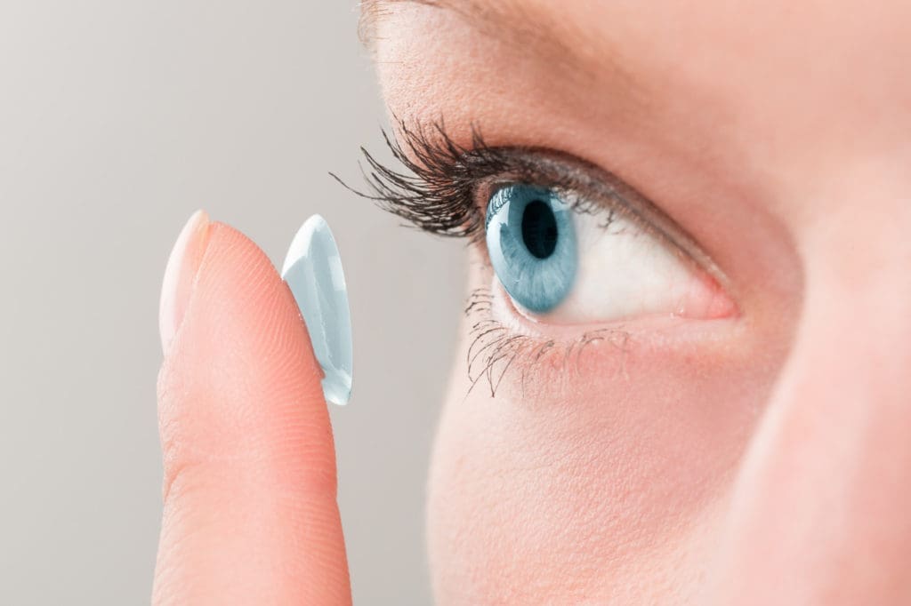 A woman is choosing and holding a contact lens for her eye.