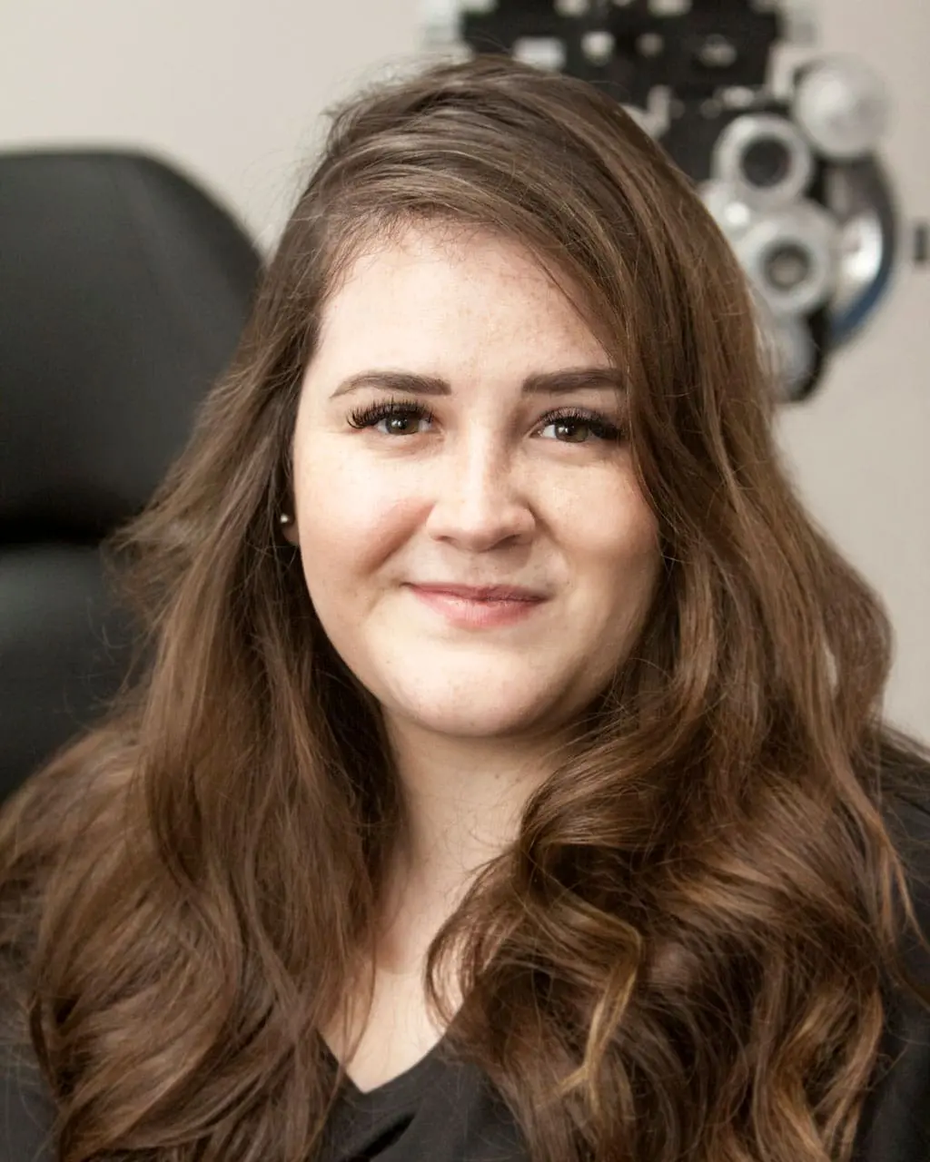 A woman smiling in front of an eye exam at Optometrist Layton.