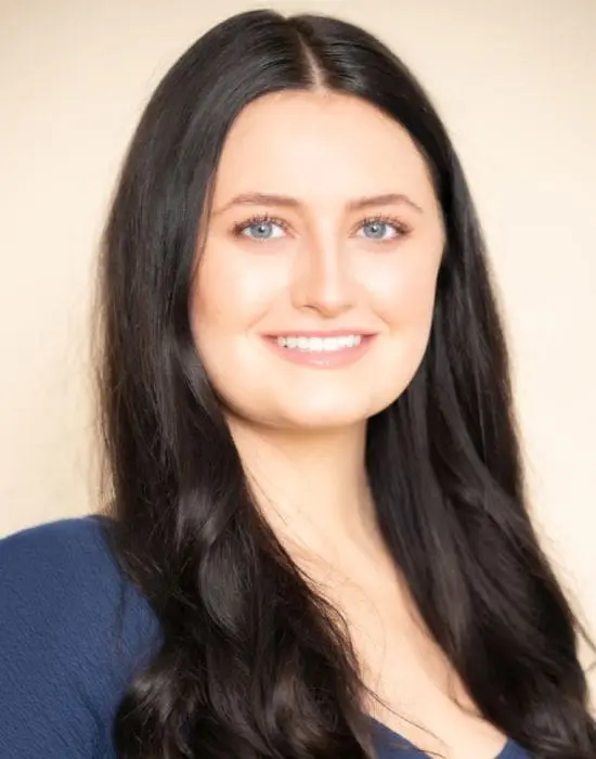 A portrait of a smiling woman with long dark hair and blue eyes, a member of the management team.