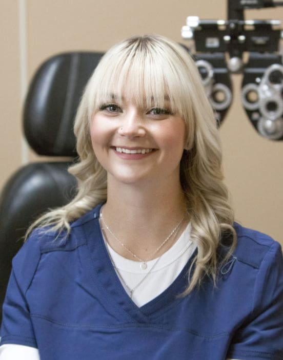 Female healthcare staff smiling in front of ophthalmology equipment in Idaho Falls.