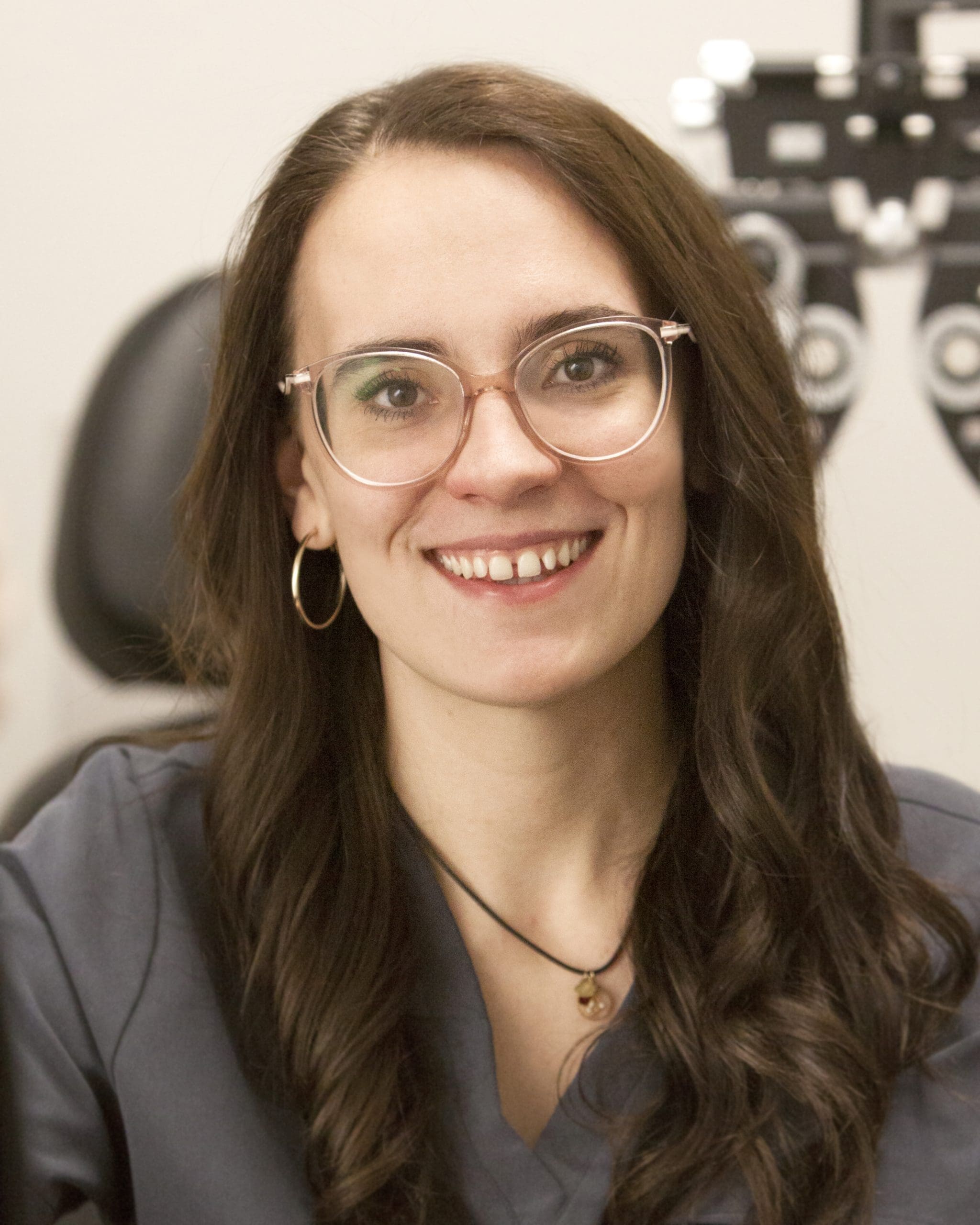 A woman in glasses is smiling in front of a computer at the Optometrist Pocatello office.