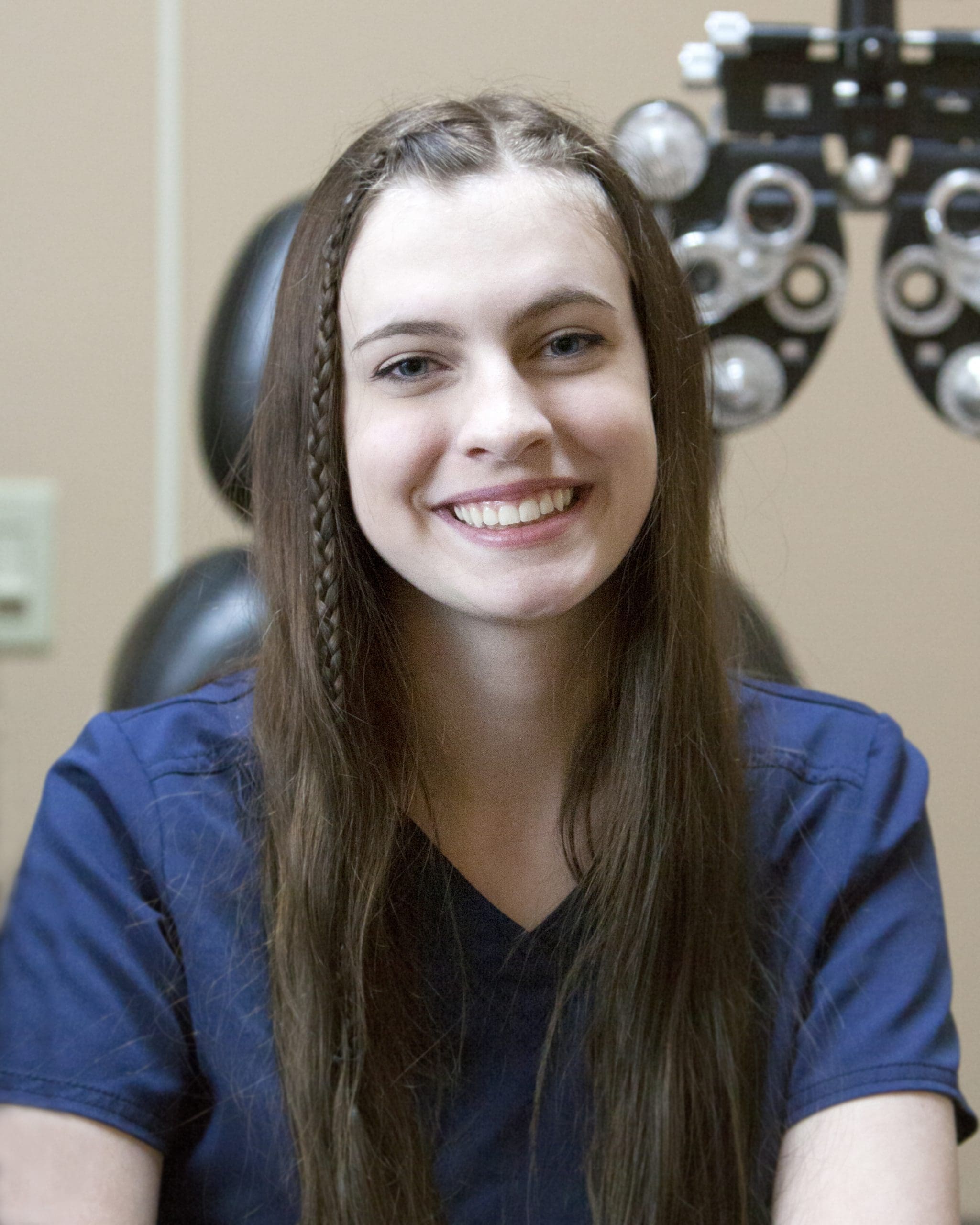 A young woman smiling in front of an eye exam at an optometrist in Idaho Falls.