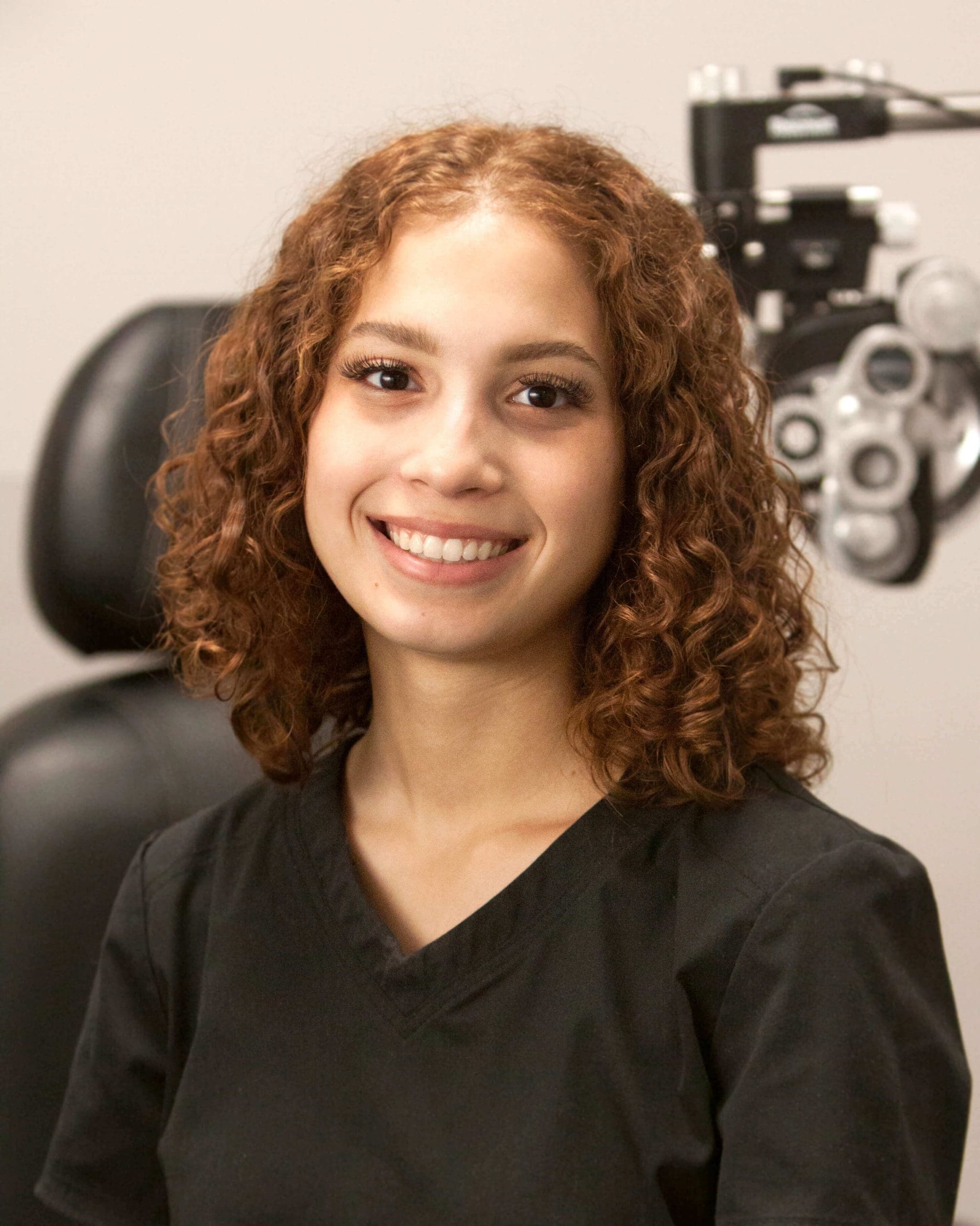 A young woman smiling in front of an eye exam at Optometrist Ogden.