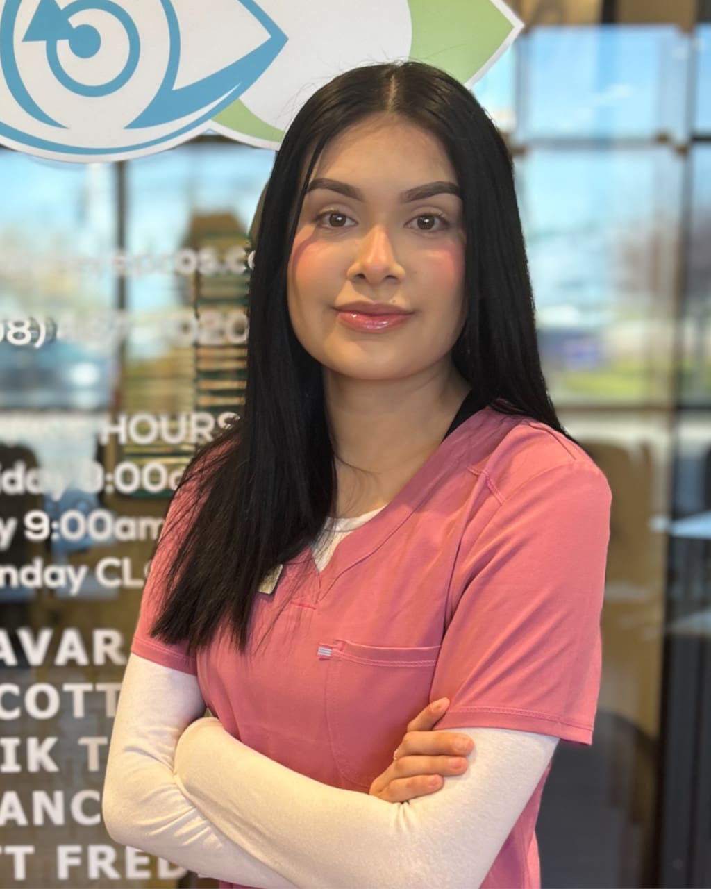 A woman in pink scrubs standing in front of an Optometrist Nampa sign.