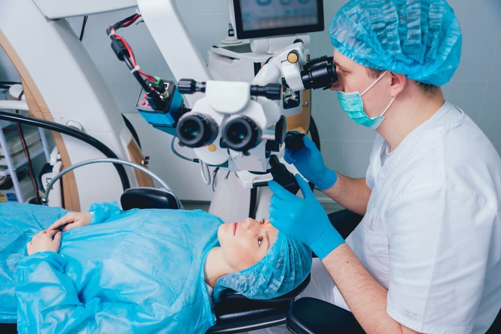Dentist in scrubs using advanced equipment to examine a patient's teeth after Lasik eye surgery.