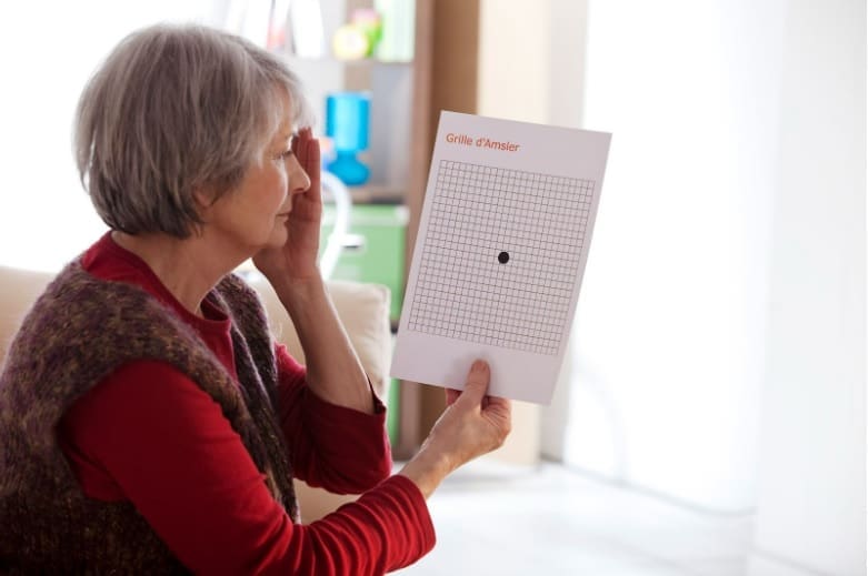 Senior woman holding an eyesight test chart due to her vision loss.