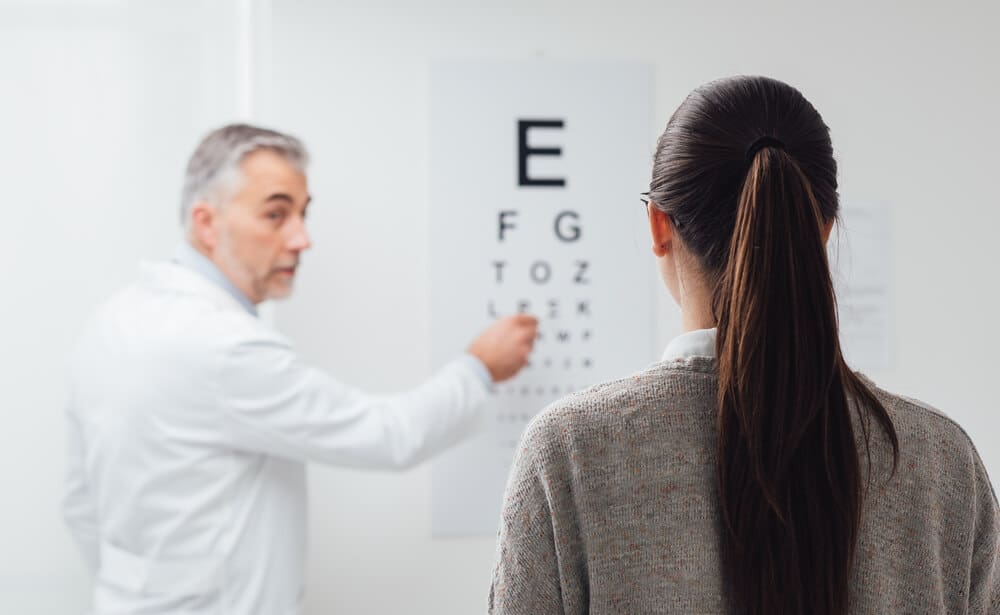 Eye doctor conducting a routine care vision test with a female patient.