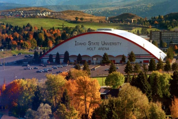 The university of Idaho's arena, nestled in picturesque locations, is surrounded by trees and mountains.