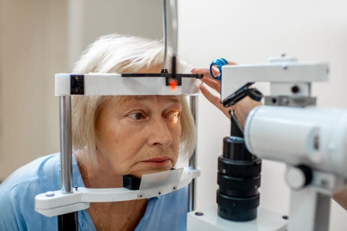 An elderly woman is having her eyes examined by an optometrist for glaucoma.