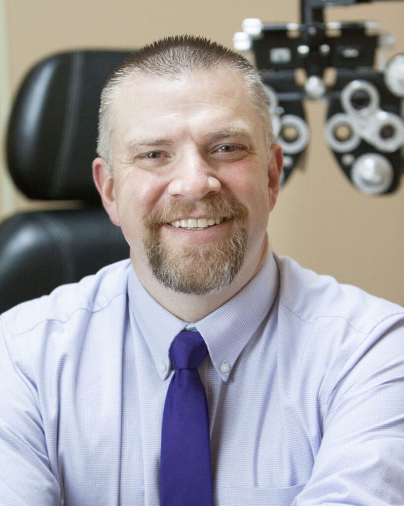 A man smiling in front of an eye exam conducted by an optometrist in Idaho Falls.