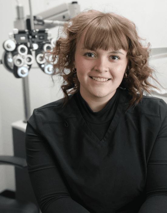 Olivia from The Eye Pros Boise Office sitting in front of an Eye Pros examination machine.