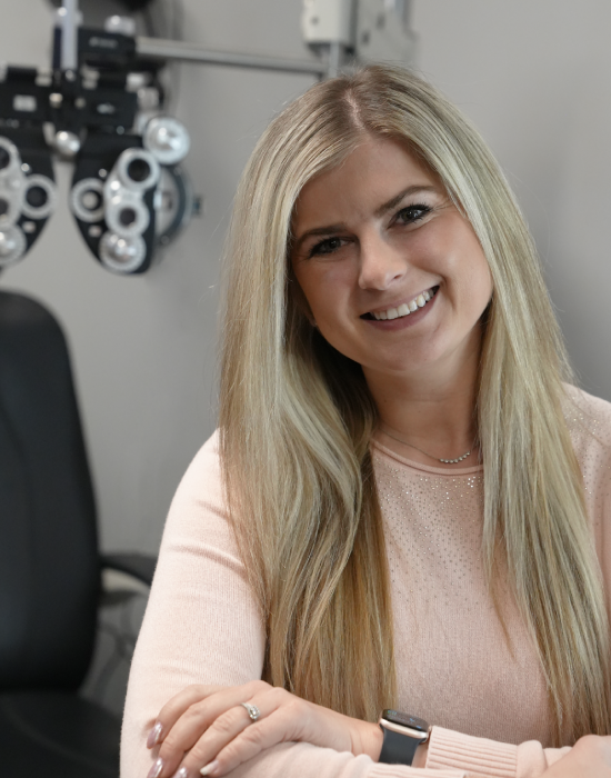 A woman with blonde hair smiling in an Eye Doctor Meridian's exam room.