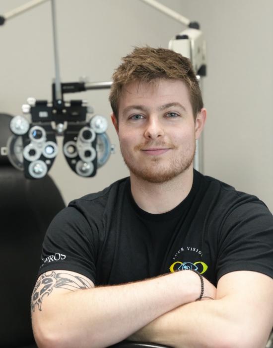 A man sitting with his arms crossed in front of an optometry phoropter at an Optometrist Nampa clinic.