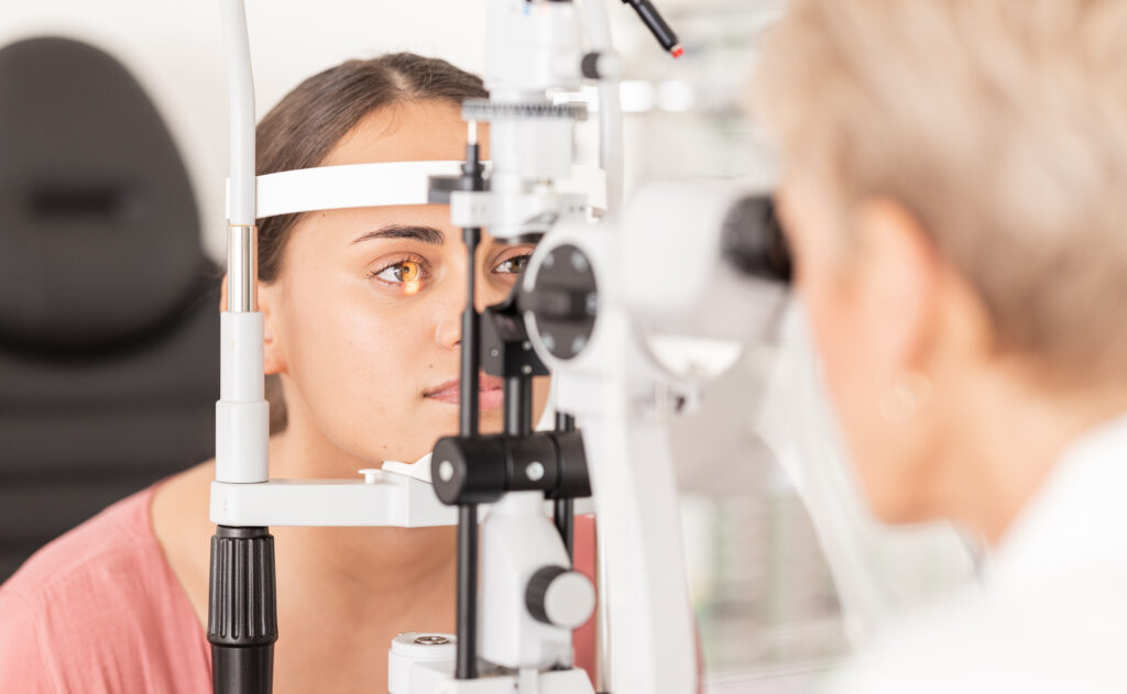 A person undergoes an eye exam using a slit lamp machine, with an eye care professional observing closely. This thorough evaluation is suitable for individuals of all ages, from kids to seniors, ensuring optimal eye health.