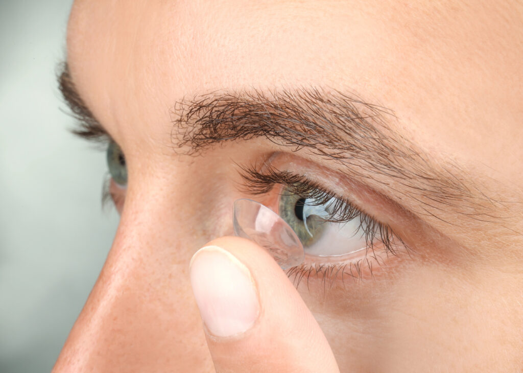 Close-up of a person inserting a contact lens into their right eye, ensuring it's the correct fit from their latest contact lens prescription.