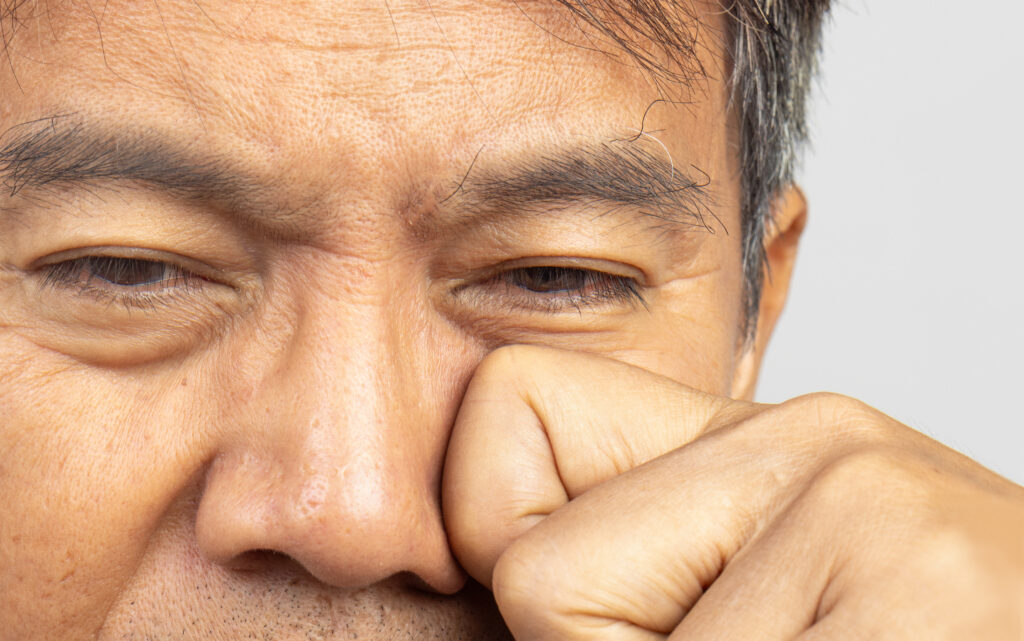 Close-up of a person rubbing their eye with a fist, appearing tired—a common cause of discomfort like dry eyes.