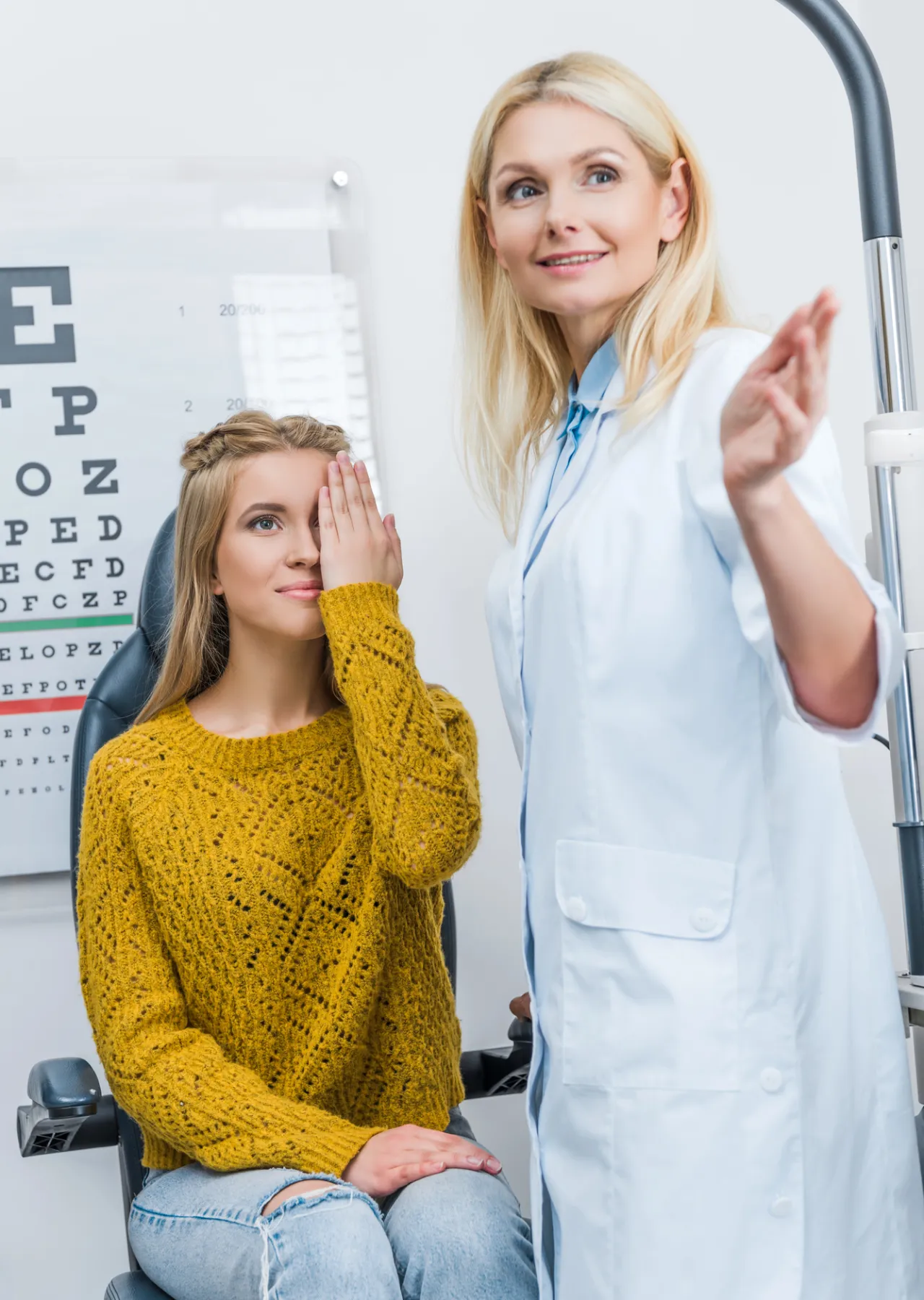 During an eye exam in Idaho Falls, a woman covers one eye as an optometrist in a white coat gestures beside her. An eye chart is visible in the background, illustrating the focus of this campaign.