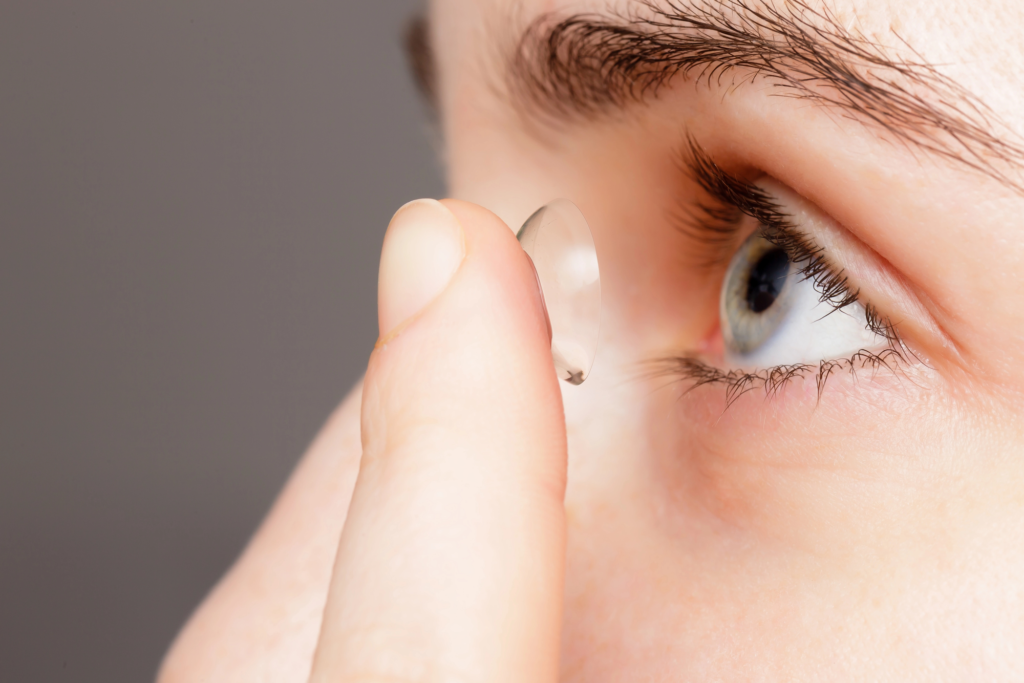 A person in Coeur d’Alene holds a contact lens close to their blue eye, preparing to insert it for enhanced comfort and looks.