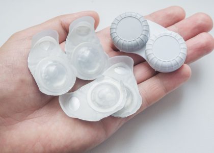 A person's hand holding a pair of disposable contact lenses, highlighting reasons to switch to disposable contacts.