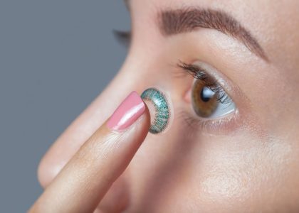 A woman is putting the best colored contacts on her eye.