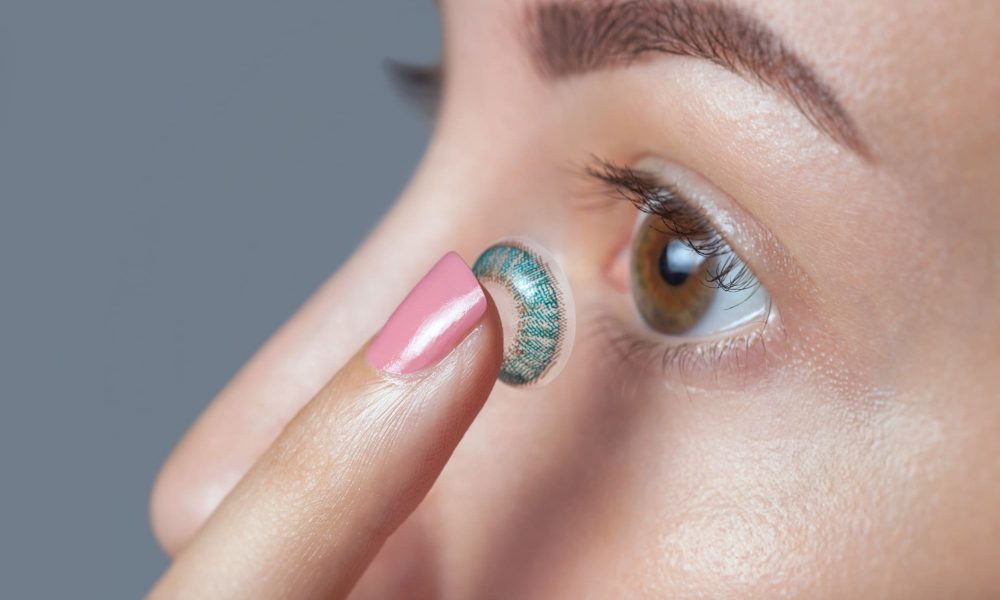 A woman is putting the best colored contacts on her eye.