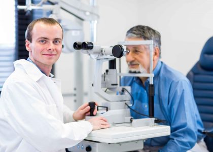 A man in a white coat is looking at a comprehensive eye exam in Idaho Falls.
