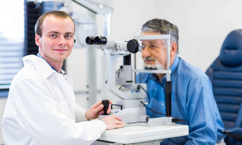 A man in a white coat is looking at a comprehensive eye exam in Idaho Falls.