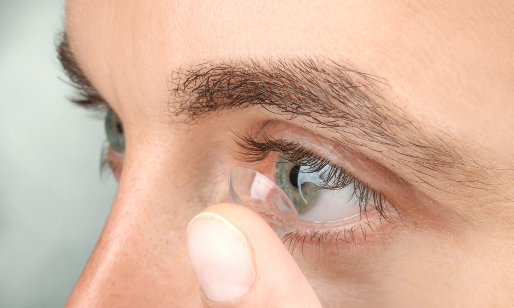 Close-up of a person inserting a contact lens into their right eye, ensuring it's the correct fit from their latest contact lens prescription.