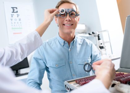 Smiling man undergoing a vision test with a phoropter during an eye exam at The Eye Pros.