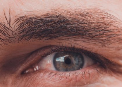Close-up of a blue eye surrounded by thick eyebrows and eyelashes, with detailed skin texture visible. After 40, watch out for changes in eye conditions that could affect such striking features.
