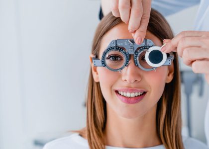 Smiling woman undergoing a vision test with a phoropter during an eye exam at The Eye Pros.