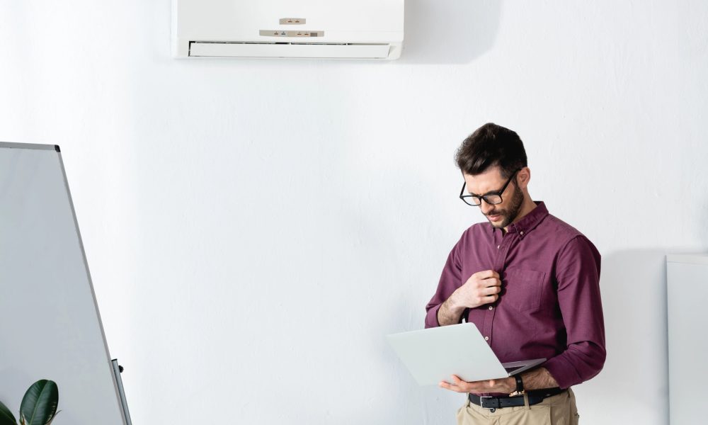 Man wearing glasses in an air-conditioned office, highlighting the importance of protecting eye health in dry, climate-controlled environments.