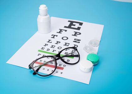 On a blue background, Vision Correction options are showcased with glasses, contact lens cases, an eye chart, and a bottle of solution.