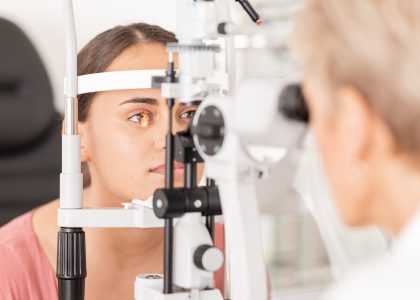 A person undergoes an eye exam using a slit lamp machine, with an eye care professional observing closely. This thorough evaluation is suitable for individuals of all ages, from kids to seniors, ensuring optimal eye health.