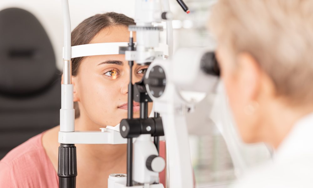 A person undergoes an eye exam using a slit lamp machine, with an eye care professional observing closely. This thorough evaluation is suitable for individuals of all ages, from kids to seniors, ensuring optimal eye health.