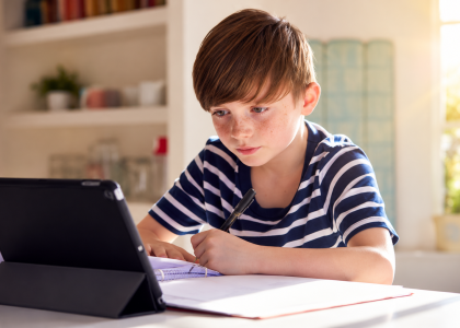 School-aged child using a tablet at home while doing homework