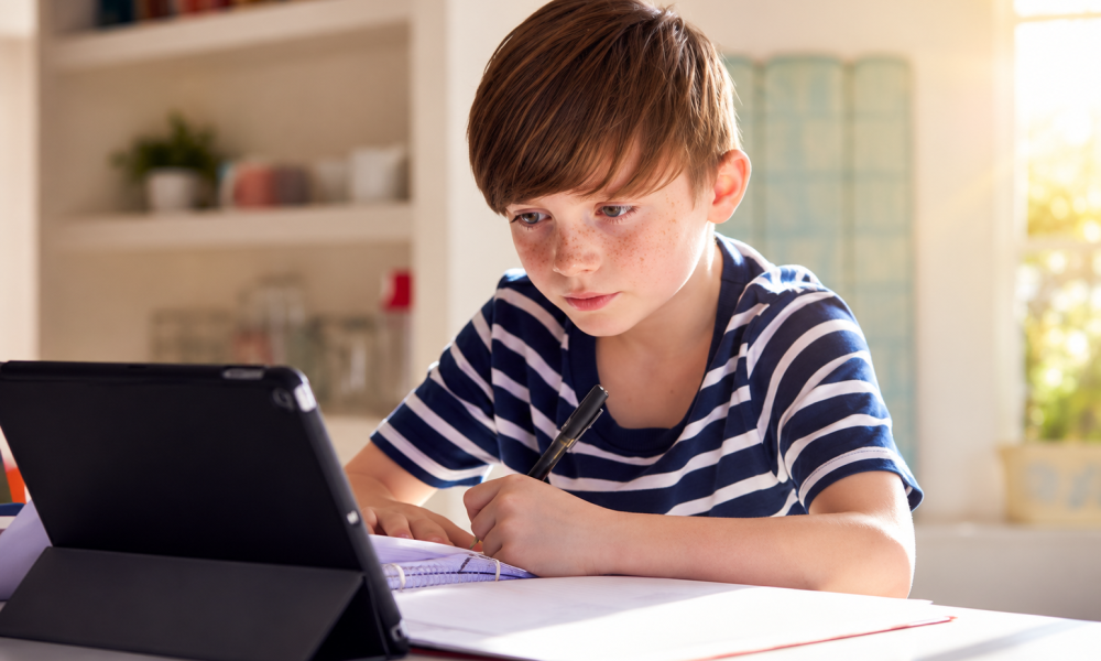 School-aged child using a tablet at home while doing homework