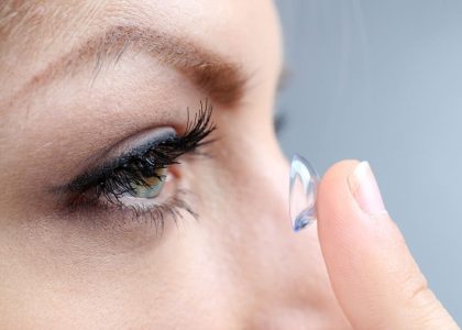 A woman is putting daily contact lenses in her eye.