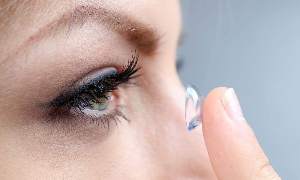 A woman is putting daily contact lenses in her eye.