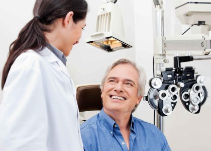 A man is smiling while sitting in front of a comprehensive eye exam machine in Nampa.