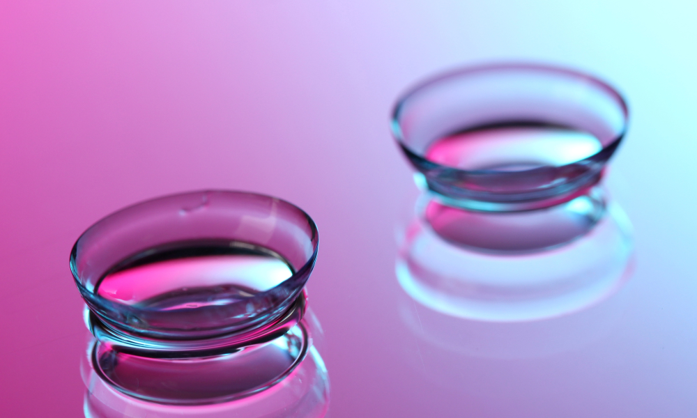 Two clear contact lenses are placed on a reflective surface with a pink and blue gradient background, showcasing both comfort and style for those seeking quality contacts in Coeur d’Alene. Two clear contact lenses are placed on a reflective surface with a pink and blue gradient background, showcasing both comfort and style for those seeking quality contacts in Coeur d’Alene.