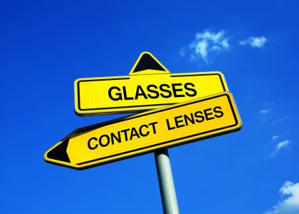 A yellow sign pointing to the options: contact lenses vs glasses.