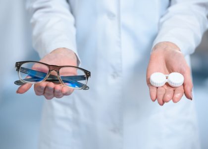 A woman in a lab coat holding a pair of contacts.